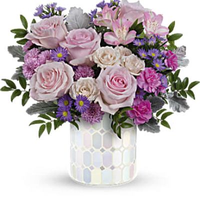 Add a touch of elegance to any space with Teleflora's Alluring Mosaic cylinder, a timeless piece that sparkles with pastel shimmer, perfectly complementing a lush bouquet of pink and purple flowers, making it a cherished centerpiece for years to come..