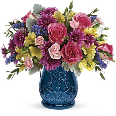 Below this bright, beautiful bouquet of pink roses and yellow alstroemeria is a cool burst of blue! This sapphire colored glass lantern, pressed with intricate details and adorned with a metal handle, is sure to be a favorite vase and candleholder.