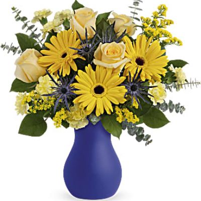 As glorious as the sunrise, this golden mix of roses and gerberas in a bold blue frosted glass vase radiates joy.